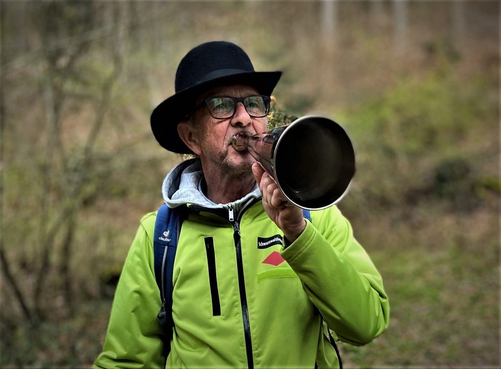 Ein Mann mit Hut vom Schwarzwaldverein spricht in eine Flüstertüte aus Messing.