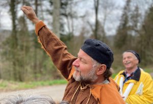 Person hebt kämpferisch einen Arm und trägt einen schwarzen, an einen Heckerhut erinnernden Hut; aufgenommen bei einer Jubiläumsveranstaltung zu 175 Jahren Badische Revolution.