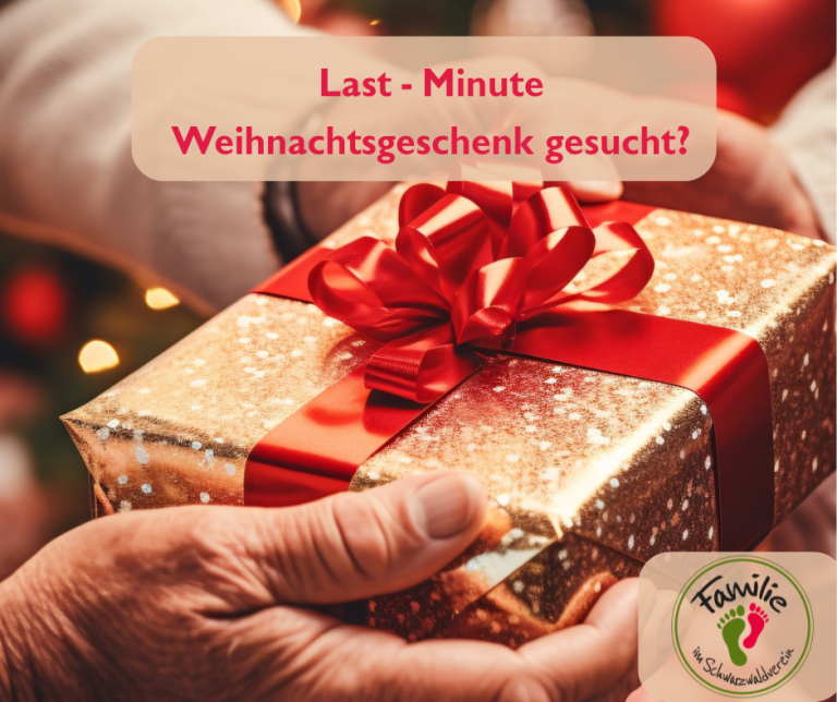 Zwei Hände halten ein Päckchen mit einer roten Schleife, das in goldenes Glitzerpapier eingewickelt ist.