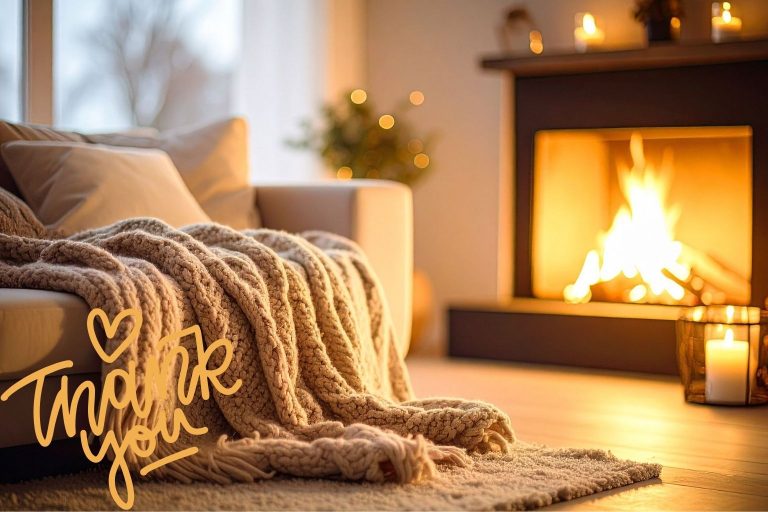 Sofa mit Kuscheldecke am brennenden Kamin.